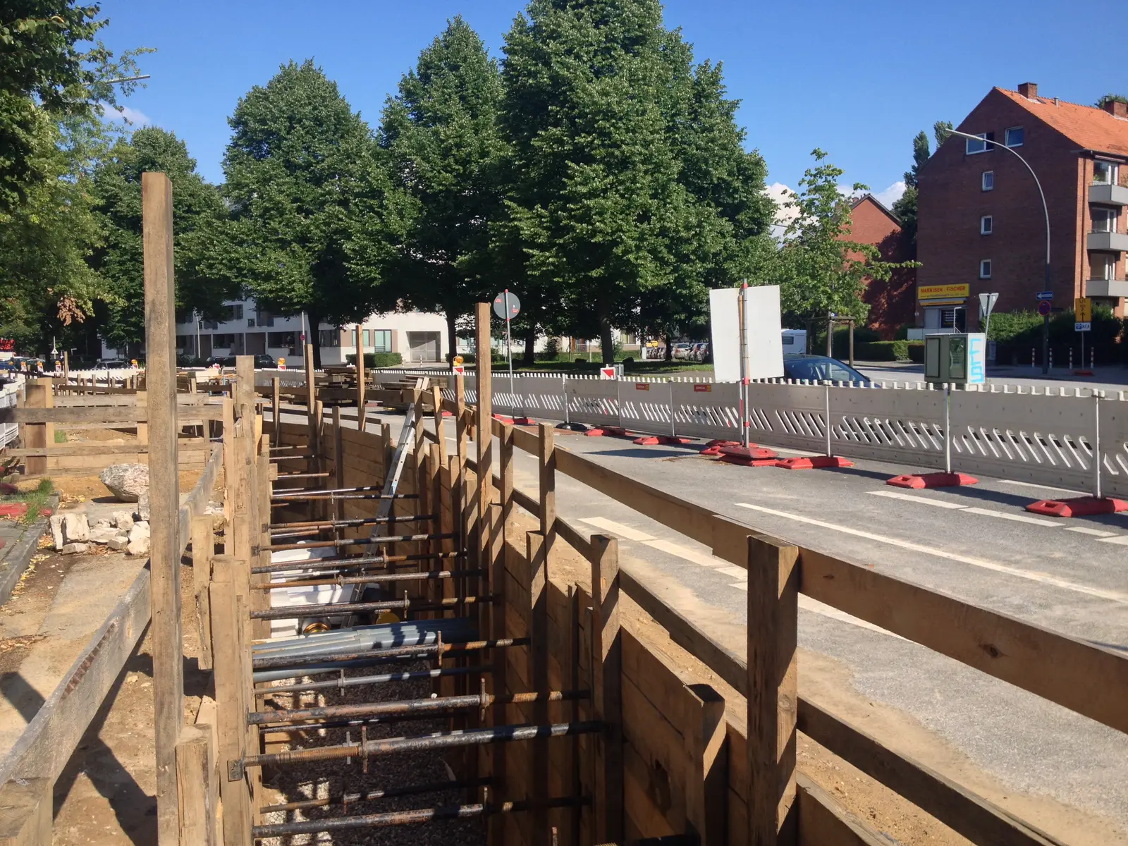 Open, timber-shored trench for a district heating distribution pipeline in an urban street